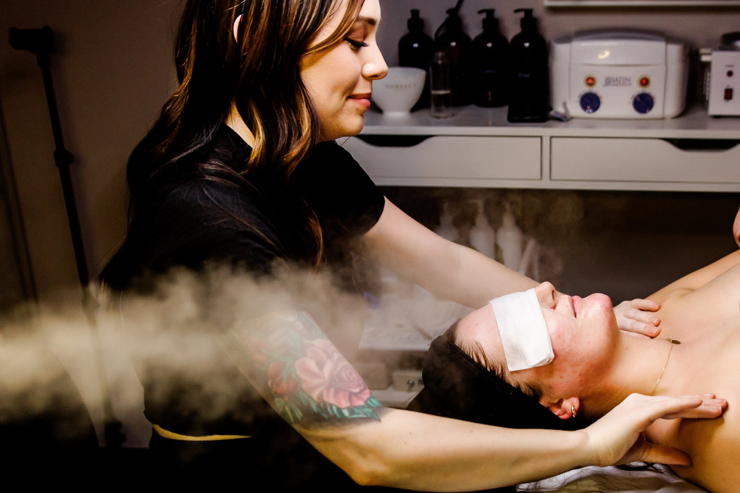 Person receiving a steam treatment from another person in a clinical setting.